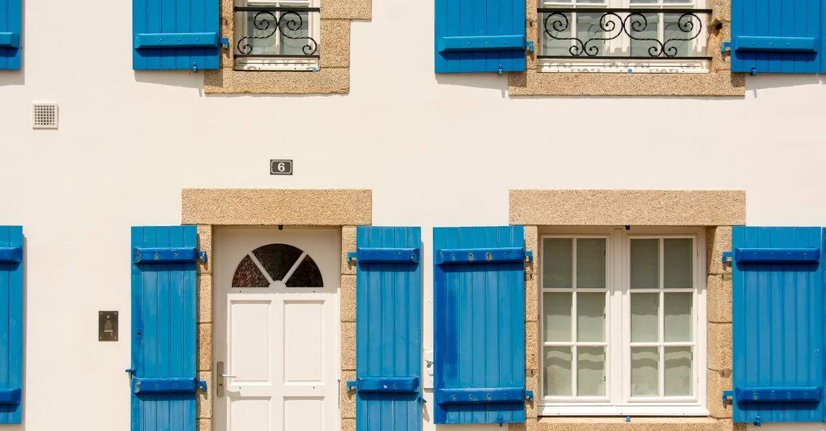 Belle façade avec des volets bleus vibrants et des fenêtres blanches pour un look classique.