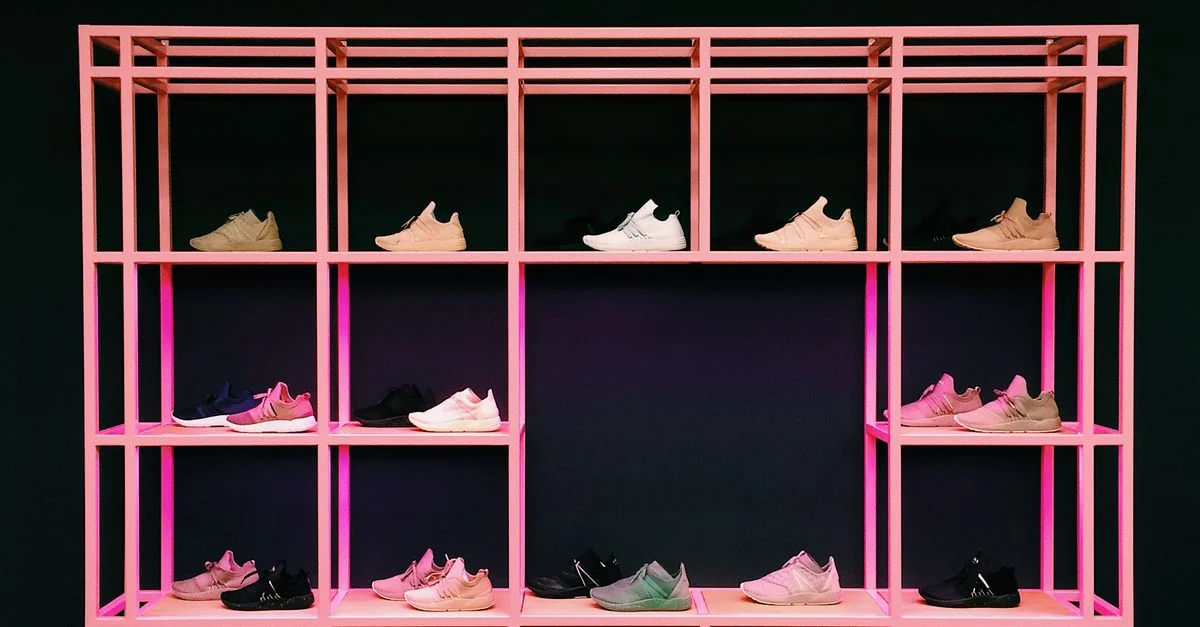 Baskets colorées disposées sur une étagère rose, mettant en avant un design et une mode modernes.
