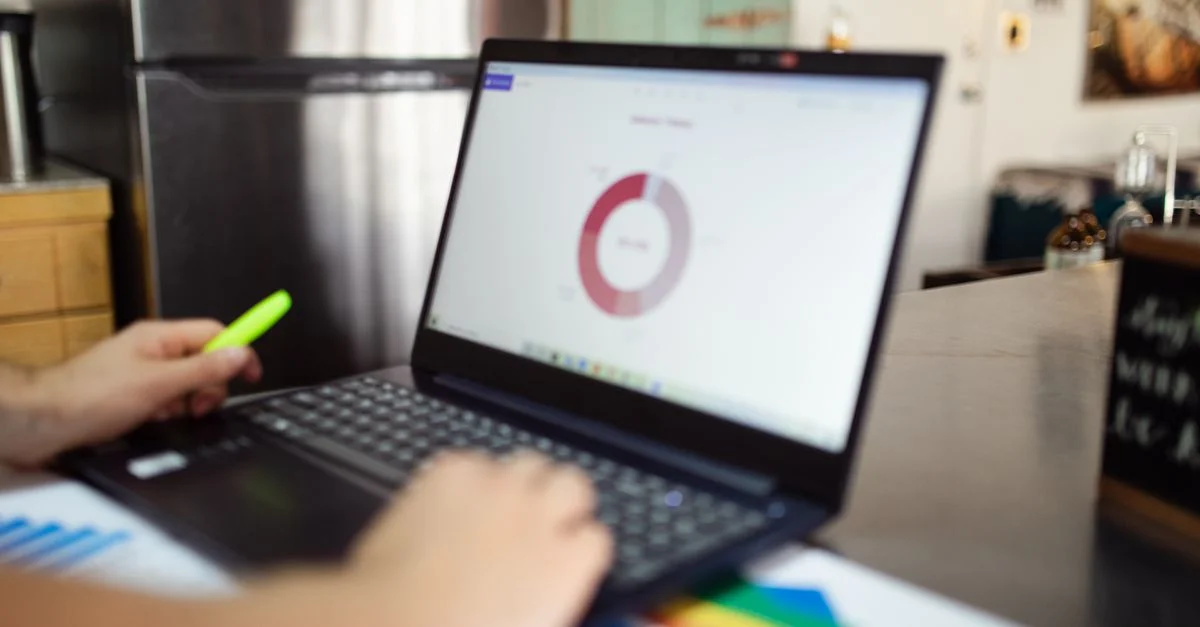 Une personne analysant des données commerciales sur un ordinateur portable dans un cadre intérieur moderne.