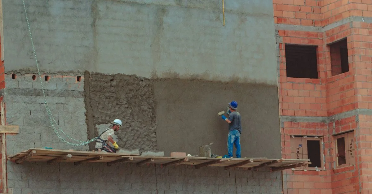 Deux ouvriers du bâtiment enduisent un mur en briques sur un site de construction.