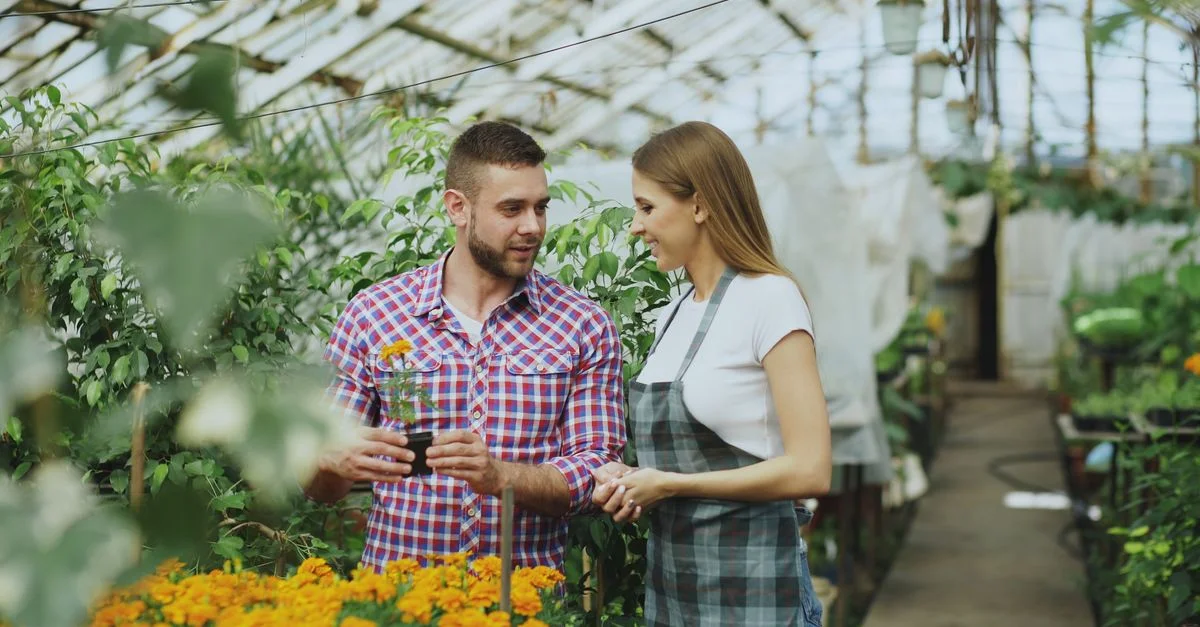 Jeunes jardiniers discutant des plantes dans un environnement de serre vibrant et luxuriant.